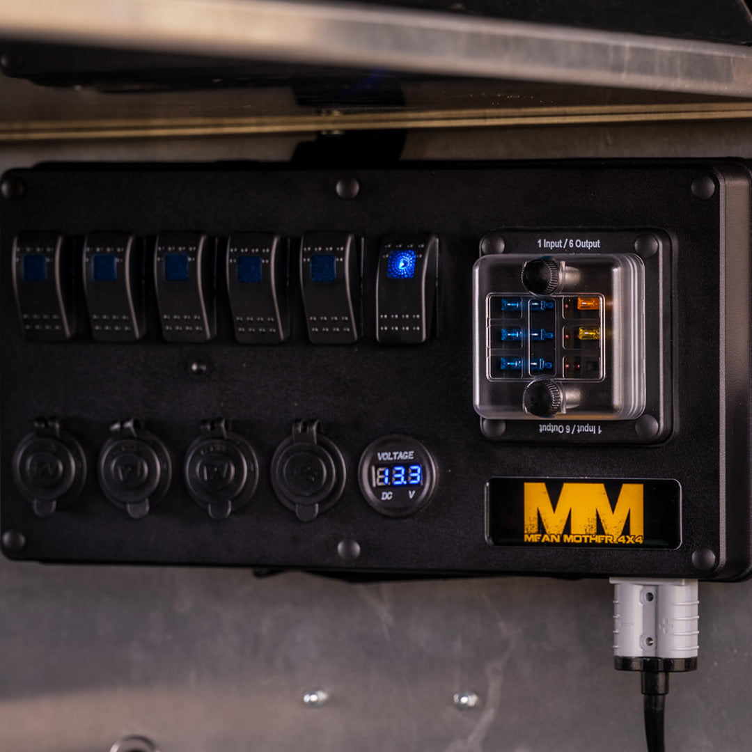 The image showcases a detailed view of the Mean Mother 12v Power Control Box. This control box is equipped with multiple labeled switches and 12V DC sockets, making it perfect for use in canopies and caravans. It also includes a digital voltmeter displaying 13.3 volts, with a noticeable "Mean Mother" logo positioned at the bottom right corner.