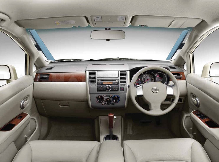 The interior of a beige car features the driver's seat, steering wheel, dashboard with sleek central console, air vents, radio, climate controls, and leather finish with wood accents. Enhanced UV protection is provided by the Sunland-Protection Car Sun Shade Interior Accordion 62cm.