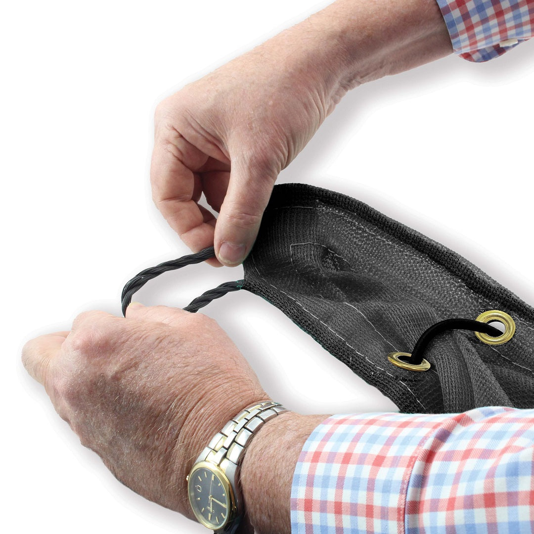 A person in a checkered shirt and silver watch holds a Cargo Mate Cargo Covers - 2x3M. One hand grips an edge with a grommet and possibly an elastic shock cord. Made of high-density polyethylene, this black mesh tarp is sturdy and ideal for trailers and utes outdoors.