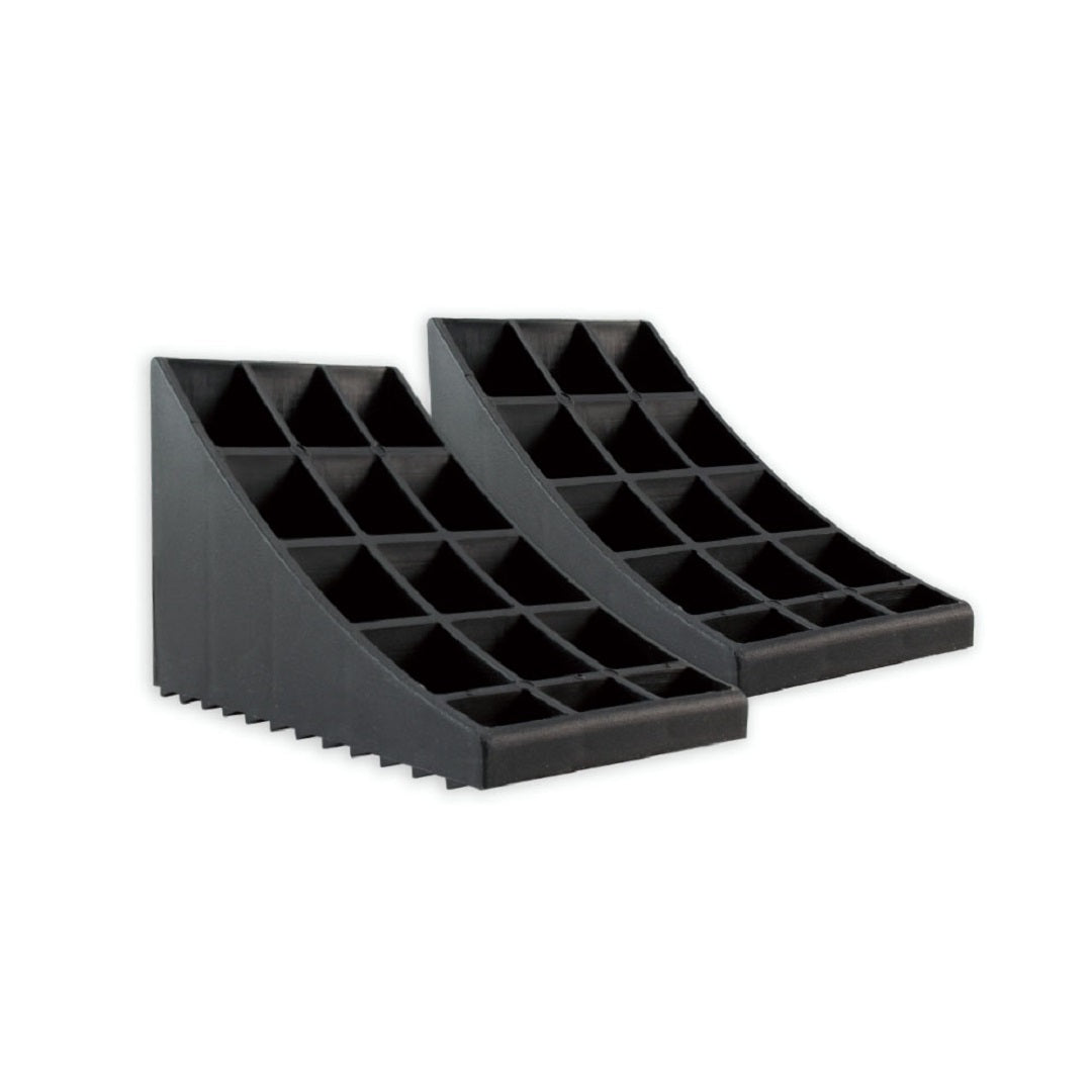 A pair of Cargo Mate Wheel Chocks With Handle by Explore, placed side by side. Each wheel chock features a grid-like structure with a series of hollow square compartments, ridged tread traction, and a sloped surface to facilitate the rolling of wheels over the edge for vehicle parking safety.