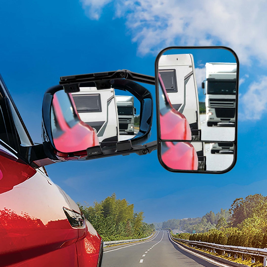 A close-up of a red car's side mirror featuring an attached Drive Multi-Fit Strap-On Towing Mirror from the brand Drive, reflecting a large white truck behind it. The car is traveling on a clear road flanked by trees, under a partly cloudy blue sky, providing enhanced visibility and effortless installation.