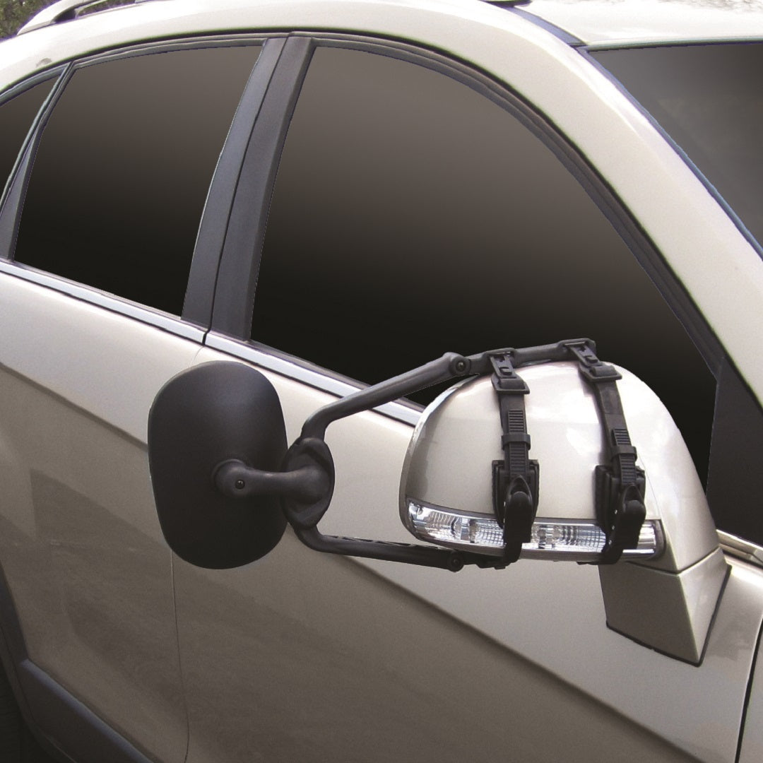 A beige vehicle showcases the Drive Towing Mirror with an extra extension, securely fastened using twin ratchet straps. The blurred background emphasizes this rear vision setup, ensuring clear visibility for all your driving needs.