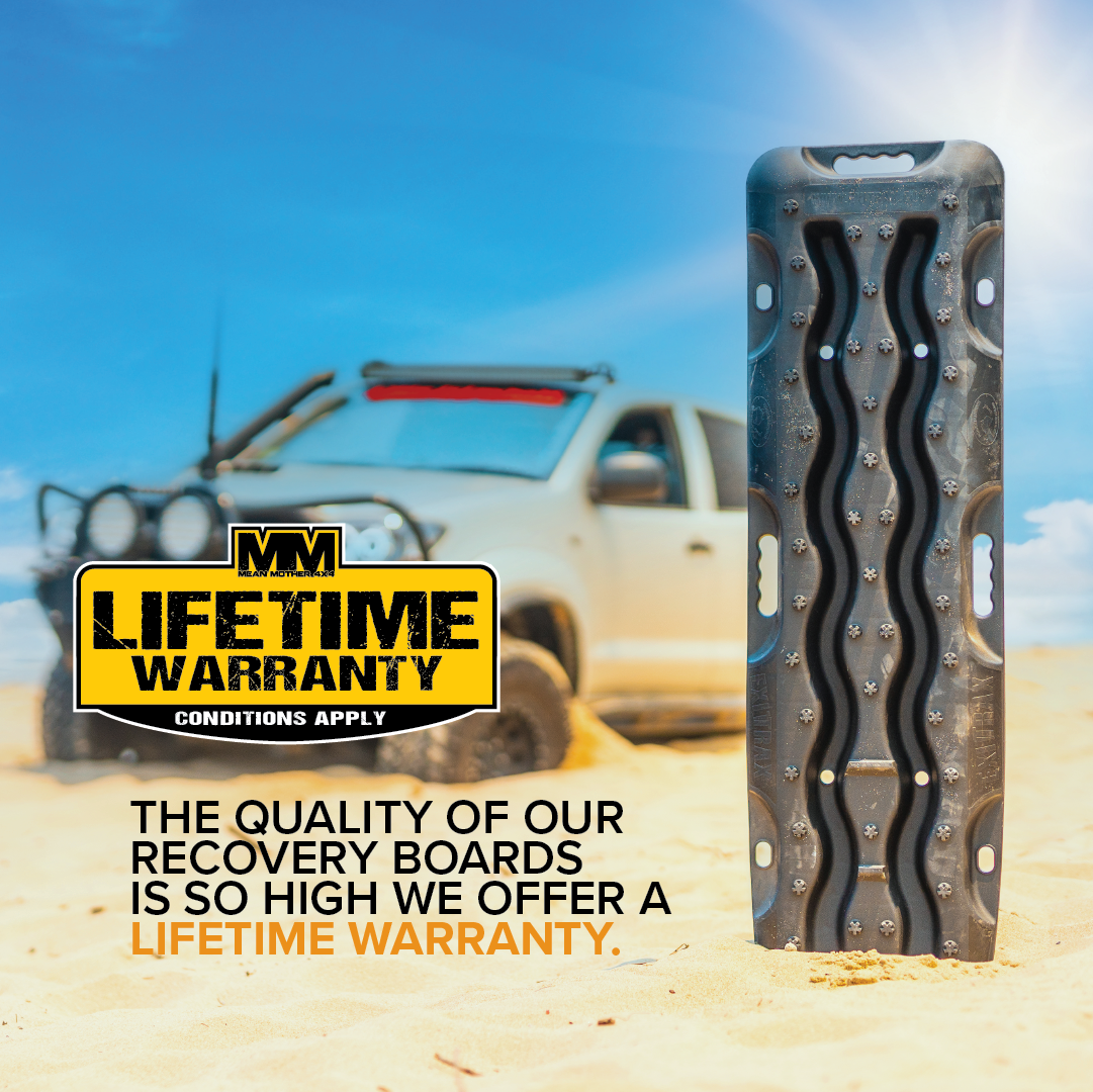 An Exitrax Recovery Board 1110 Series - Black stands upright in sand with an off-road vehicle blurred in the background. Text reads, "Lifetime Warranty. Conditions Apply." The quality of our 4x4 recovery boards and mounts bundle is so high that we offer a lifetime warranty.