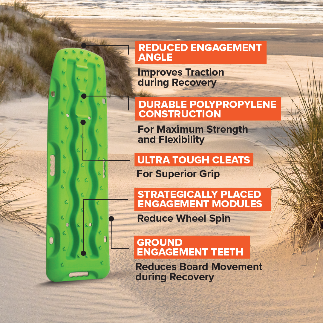 An Exitrax Recovery Board 1110 Series - Black, Pair, featuring traction enhancement, a reduced engagement angle, durable polypropylene construction, ultra-tough cleats, strategically placed modules, and ground engagement teeth with a lifetime warranty is placed on sandy terrain by the sea.