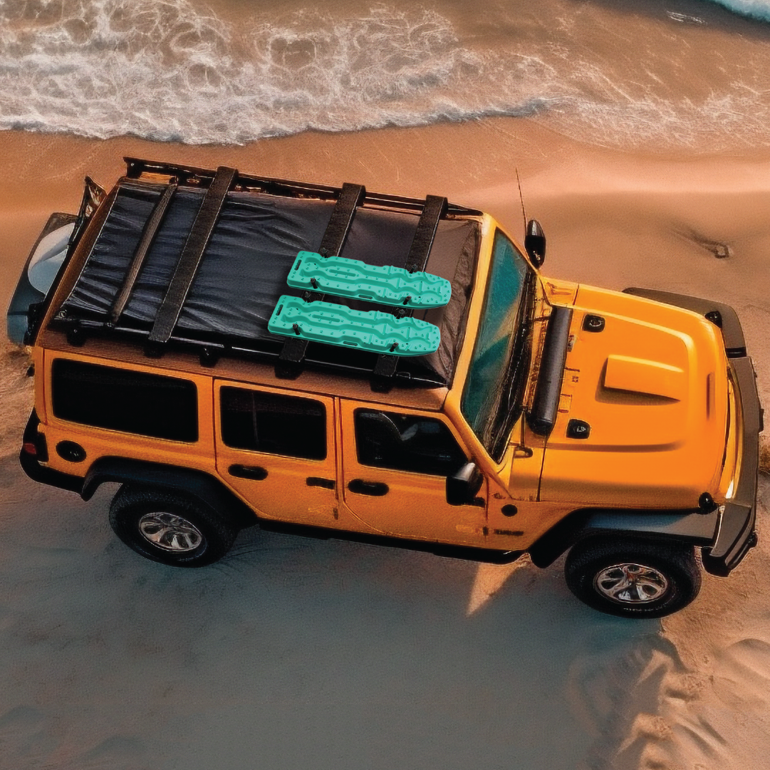A yellow off-road vehicle is parked on a sandy beach with waves in the background. Equipped with a corrosion-resistant nylon roof rack, it carries two green recovery boards using the Exitrax Recovery Board Mounting Kit by Exitrax, ensuring your adventure by the sea is always prepared for the unexpected.