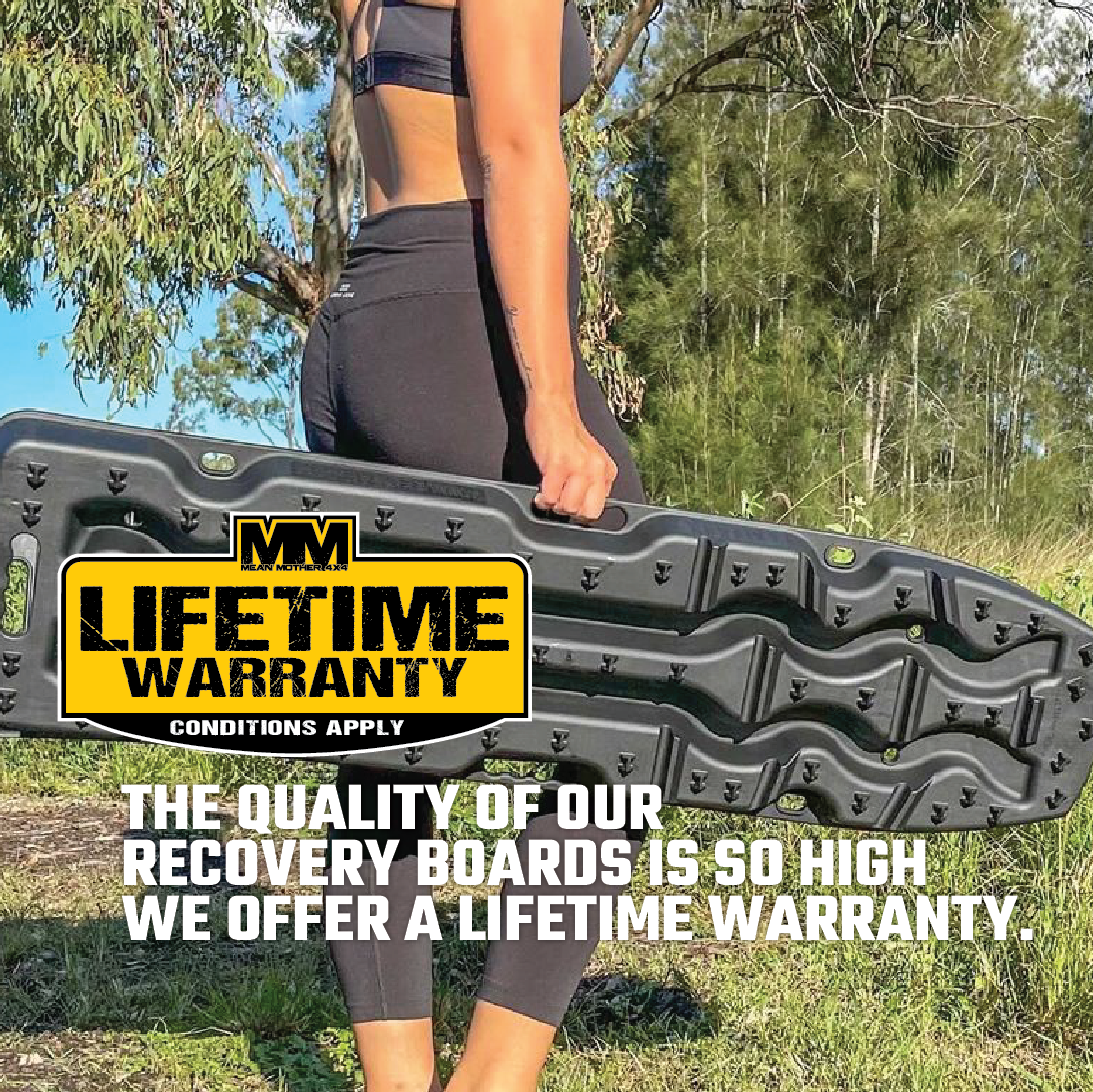 Wearing athletic gear, a person holds an Exitrax Recovery Boards Ultimate 1150 - Black outdoors among trees and grass. Text: "Lifetime Warranty. Conditions apply. Exitrax offers a lifetime warranty on our high-quality recovery boards.