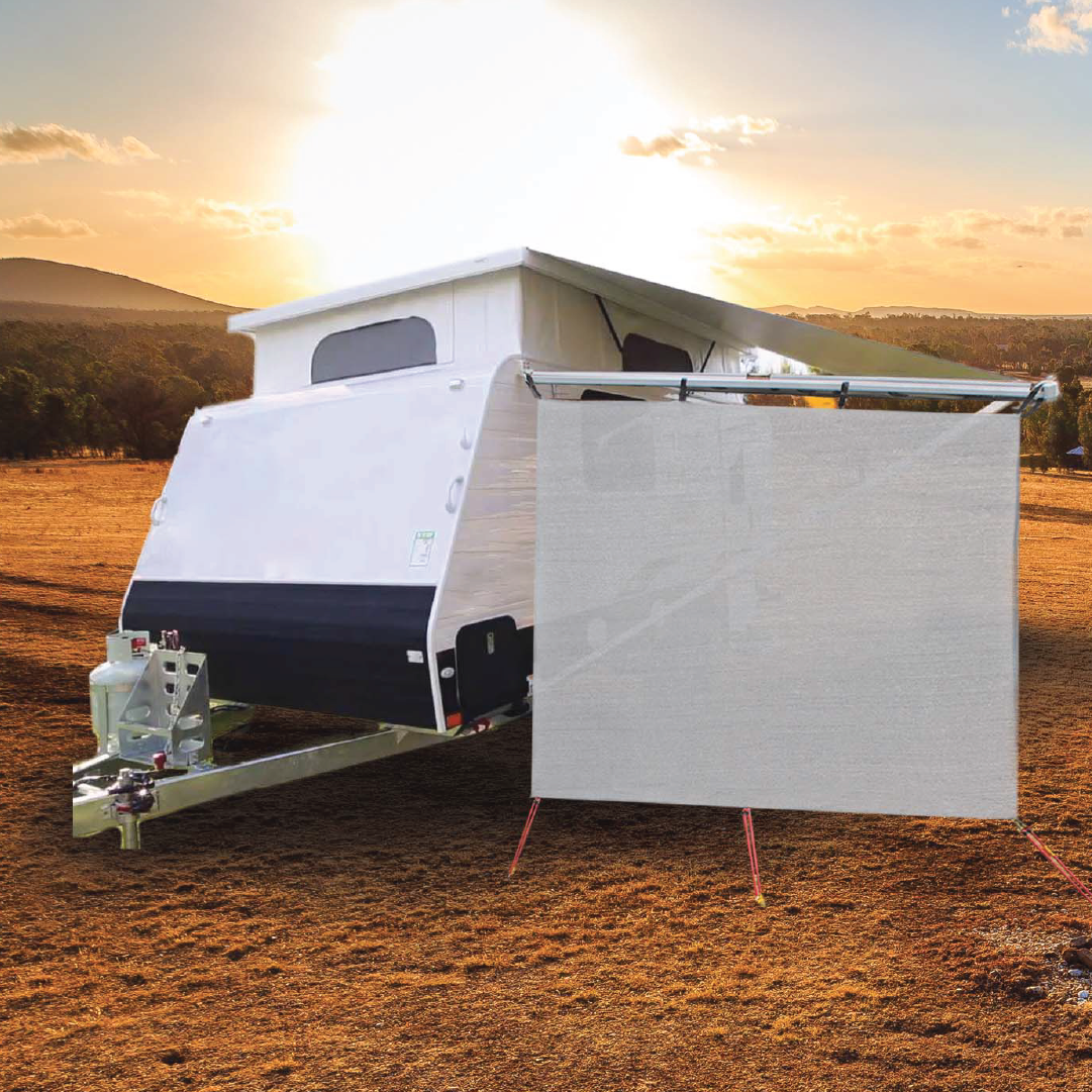 An Explore compact pop-up camper trailer is set up in an open, dry landscape during sunset. Part of the camper is shaded by an extended awning, while a privacy screen is securely attached to the metal frame with sturdy Explore Hard Surface 8 Pce Metal Screw Pegs from the Explore brand. The sun casts a golden hue over the scene.