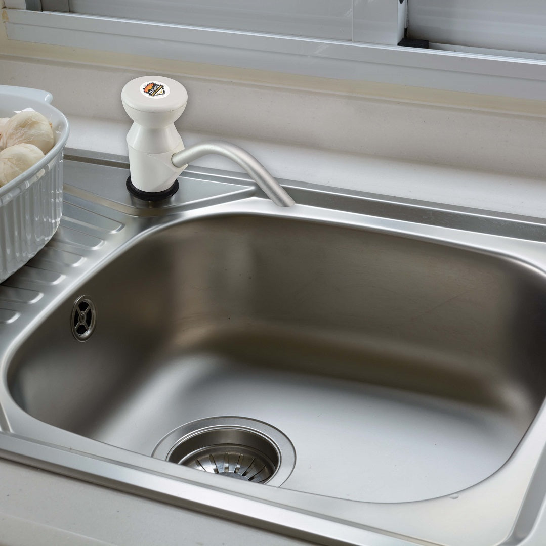 A Caravan Sink Pump in white from Explore highlights its corrosion resistance with a sleek stainless steel kitchen sink, complete with a single spout tap. Nearby, a soap dispenser sits on the counter, while mushrooms rest on the left side, blending functionality with style.