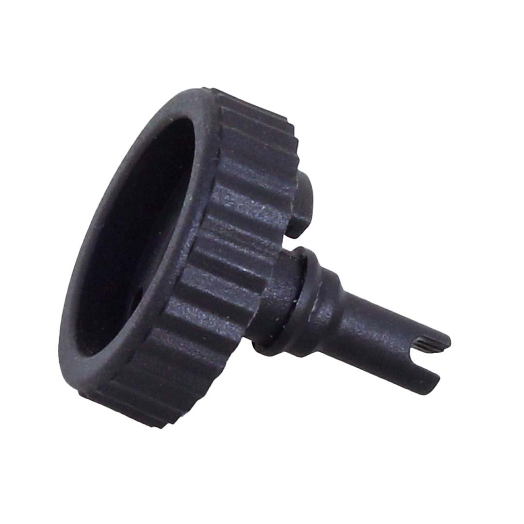 Close-up of a safety lock cap from the Liquid Patch Tyre Puncture Repair - 250ml, featuring a black, circular plastic component with a ridged edge and a cylindrical protrusion with a notched end for enhanced puncture protection.