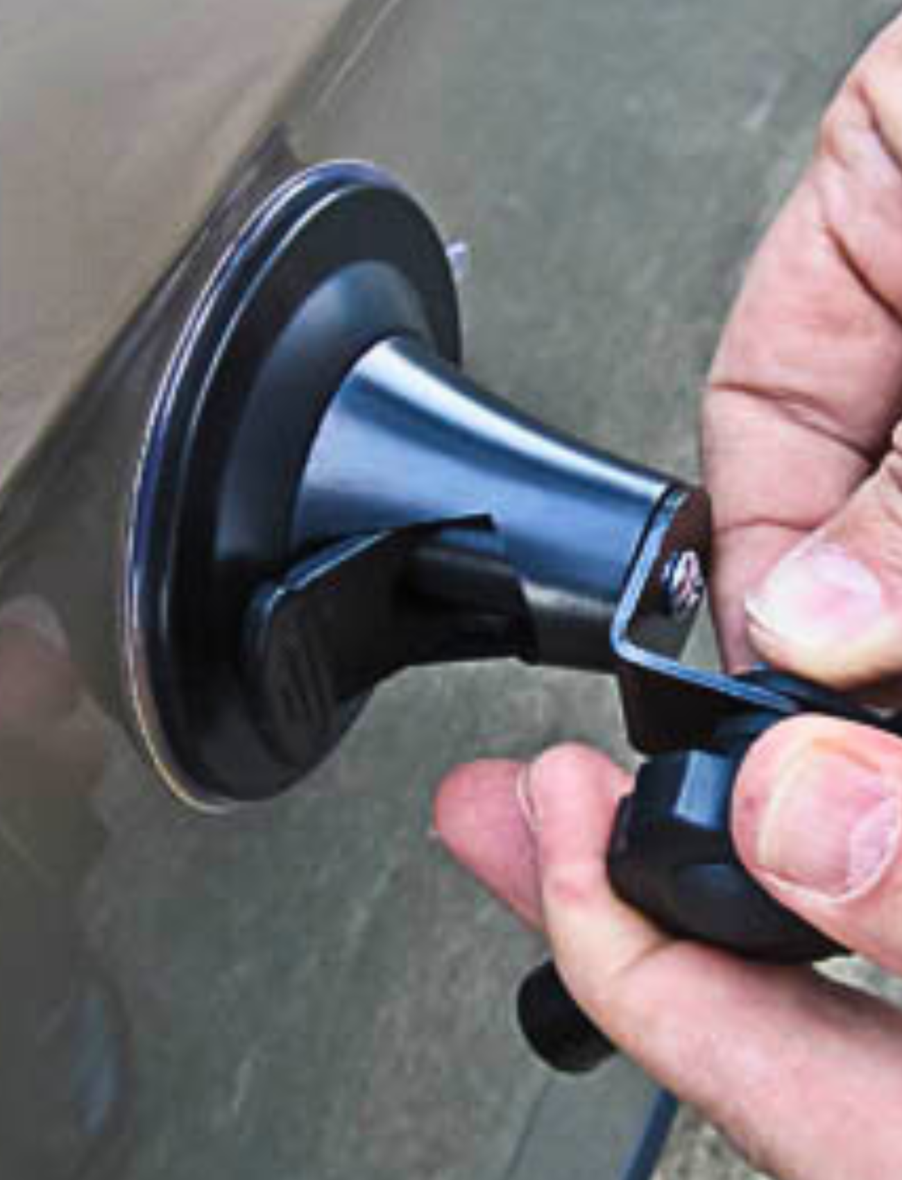 Close-up of hands using a Sunland-Protection MIRROR TOWING SUCTION CUP - SUITS MH3007 on a car's surface. The suction cup features a black handle and attaches firmly to the car body, indicating repair in progress.