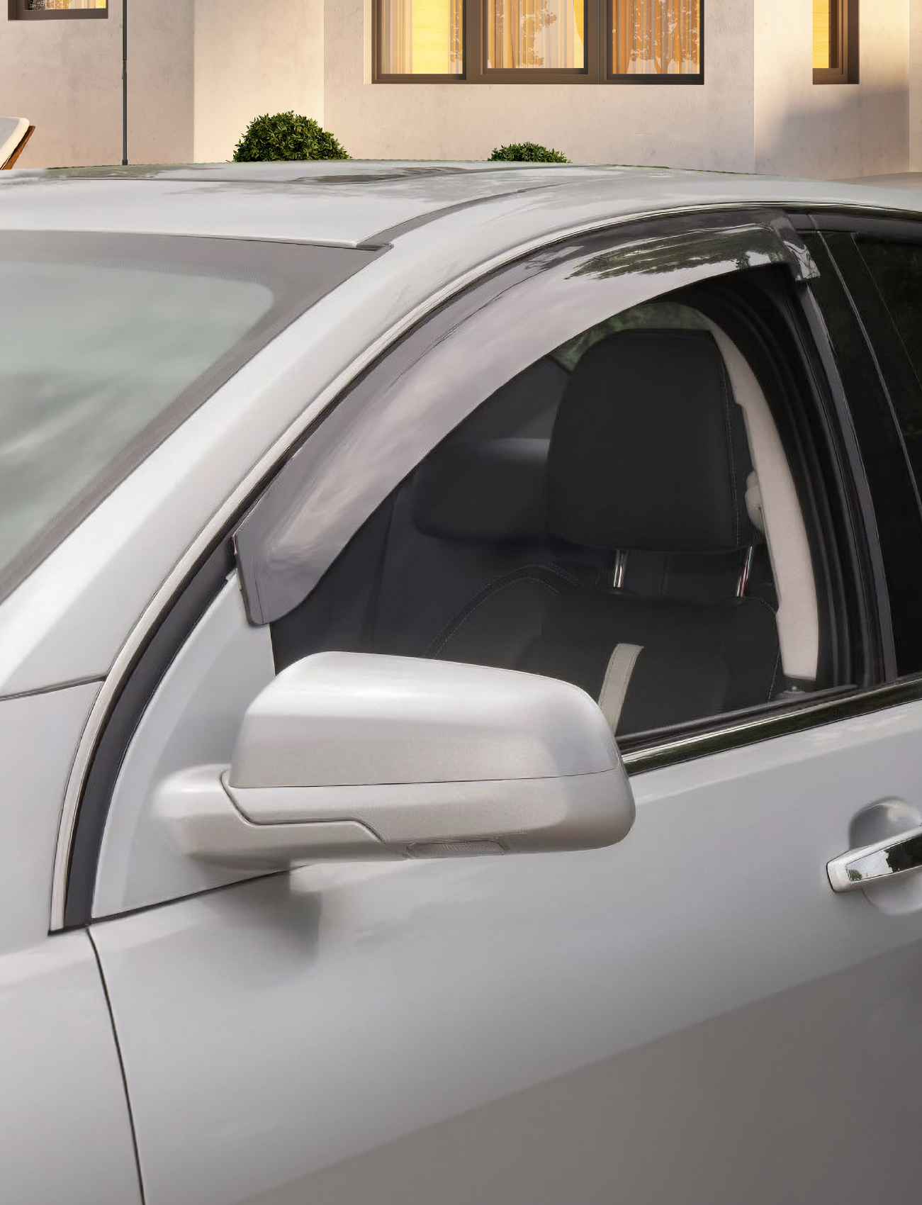 A close-up of a Ford Falcon EF/EL sedan’s side mirror and front window fitted with Sunland Protective Plastics Weathershield Slimline Light Tint (F260SLP), parked before a modern building with large windows and trimmed bushes.