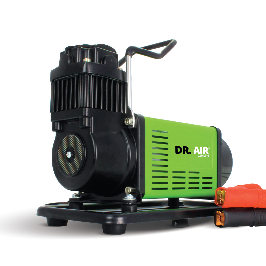 A compact and powerful 12V air compressor, the Mean Mother 4x4 110 LPM, features a sleek green and black design labeled with its brand name. It comes equipped with a sturdy metal handle on top for easy transport and includes red and black alligator clamps for power connection.