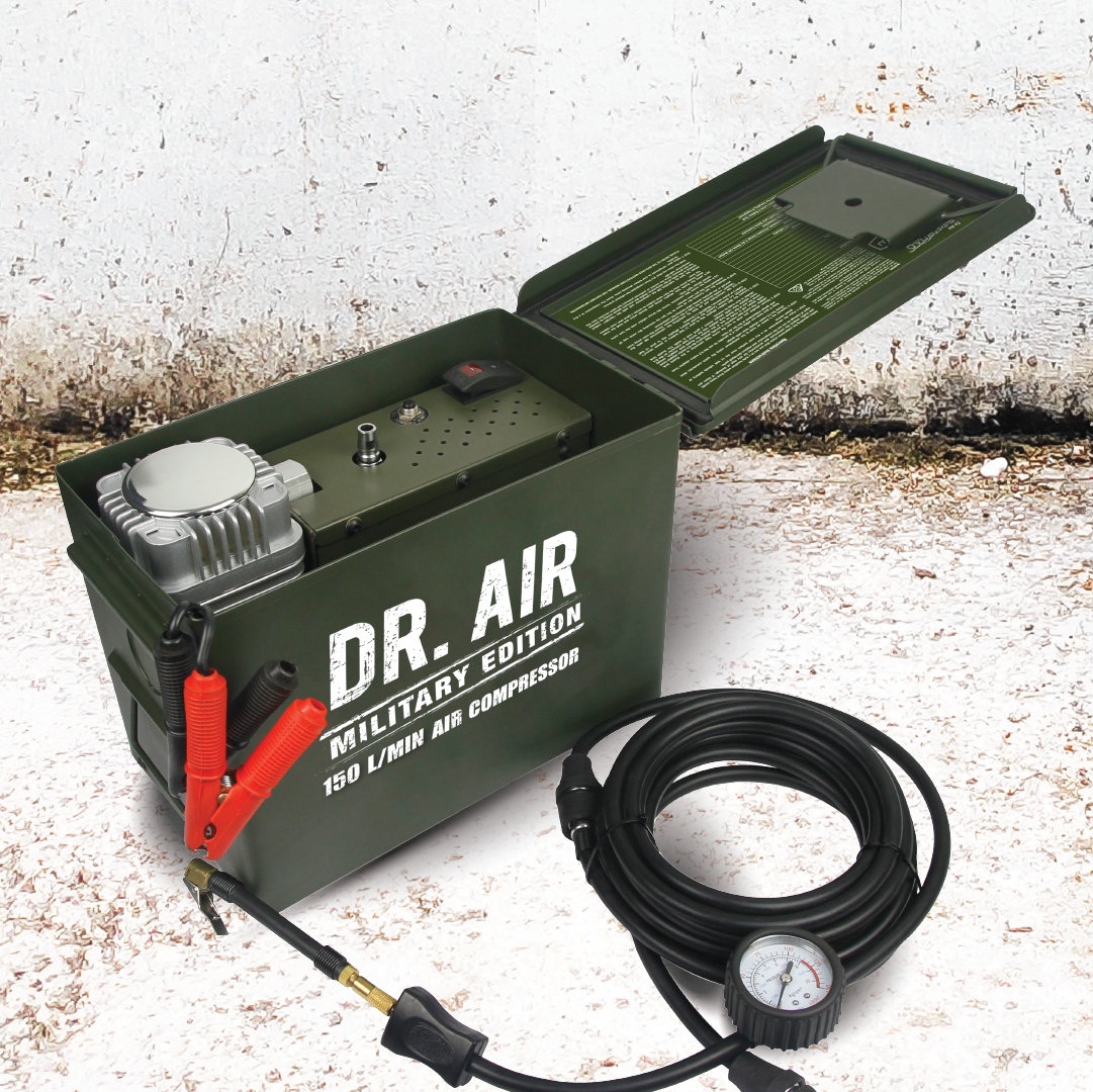 A green air compressor labeled "Dr Air Ammo Box" includes red and black cables, a pressure gauge, and a coiled black hose. Designed with heavy-duty ammo housing, this military-tough 4WD air compressor, capable of delivering 150 Lpm, sits on a textured concrete surface.