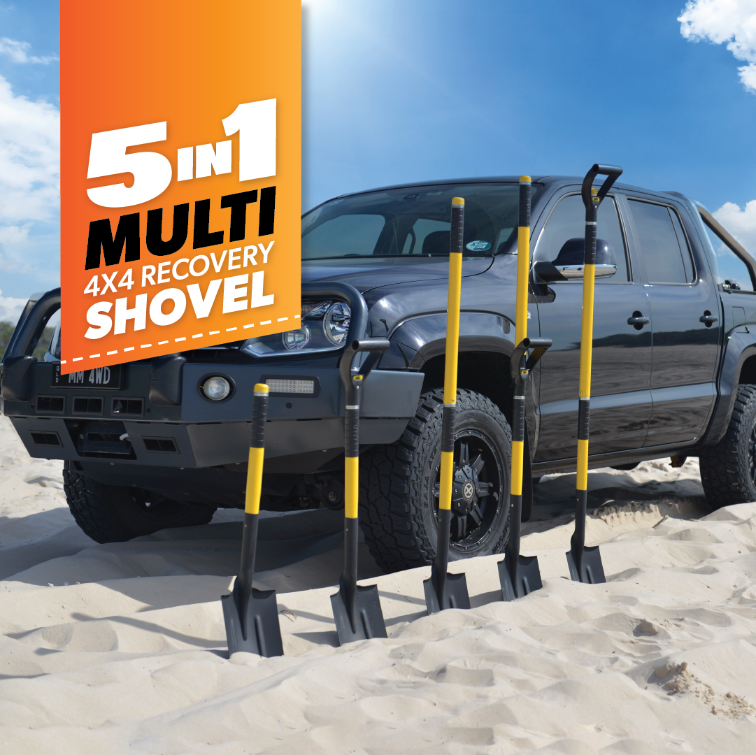 A black 4x4 vehicle is parked on a sandy beach under a blue sky. Beside it, five yellow and black shovels stand upright in the sand. An orange banner announces "5-IN-1 Multi 4x4 Recovery Shovel" by Mean Mother 4x4, making this the ultimate beachside recovery tool.