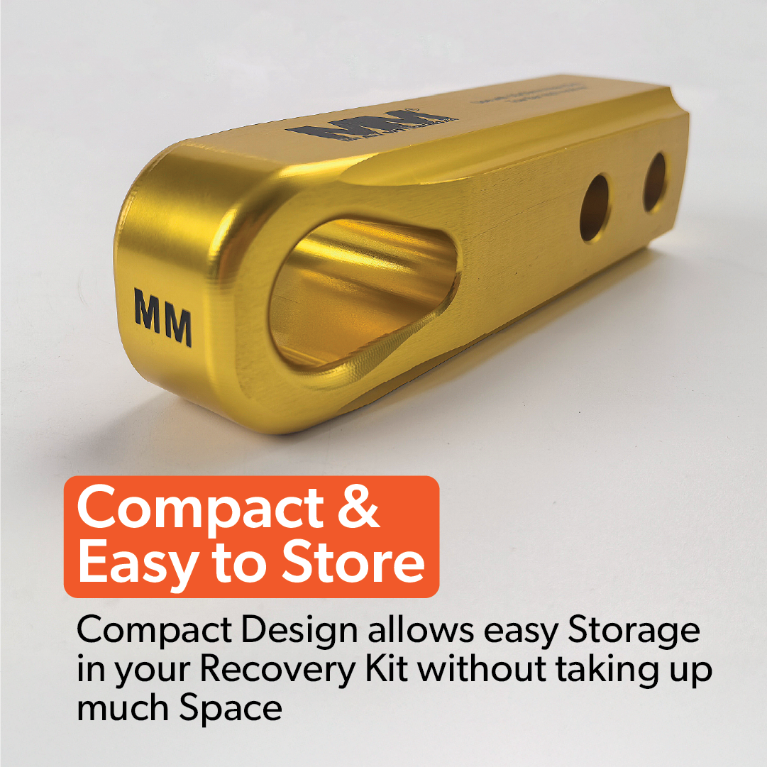 A Mean Mother 4x4 Recovery Hitch, crafted from gold billet aluminium and engraved with "MM", sits on a white surface. Its compact design saves space, making it ideal for easy storage in any 4WD recovery kit.