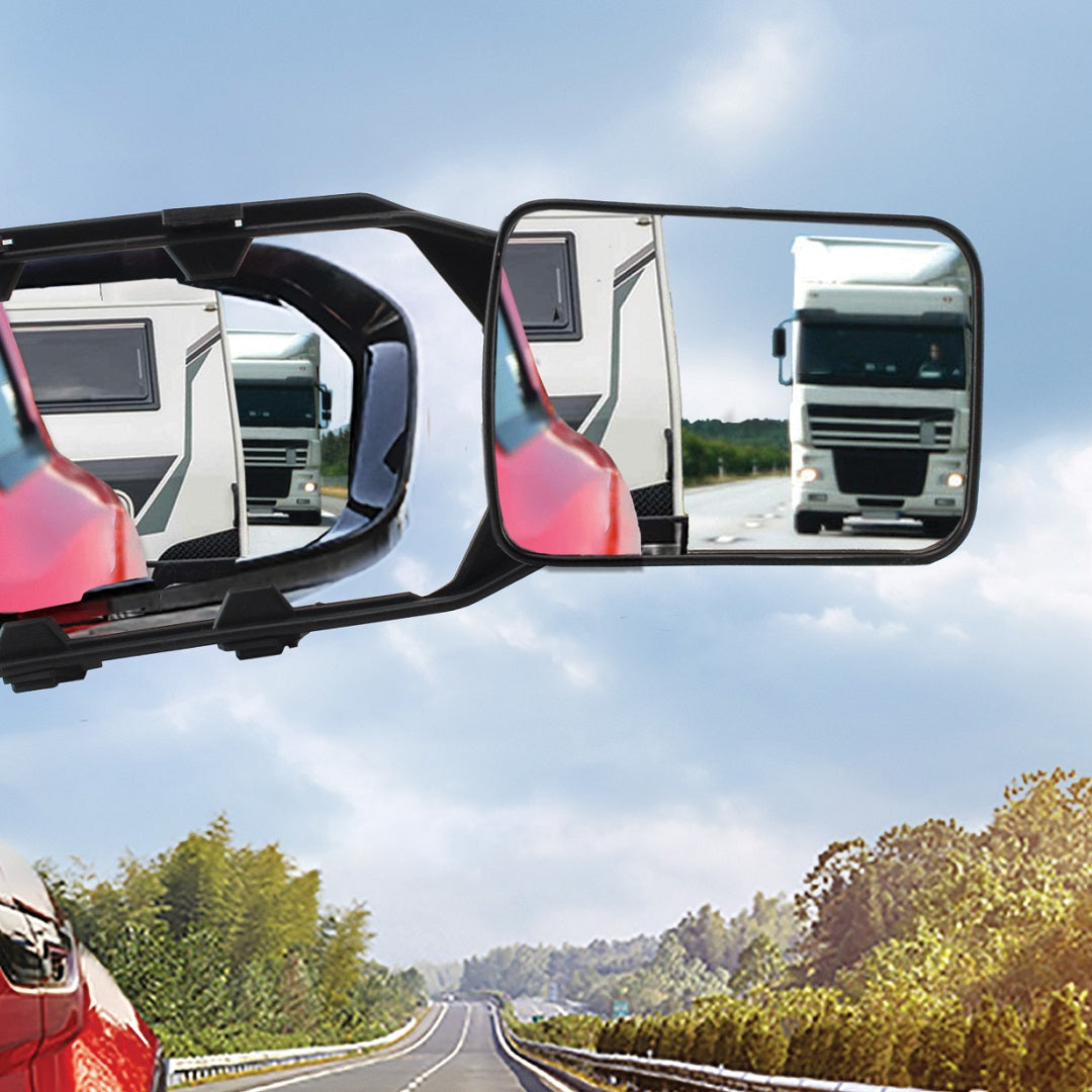 A view through a vehicle's side mirrors, enhanced with Drive Multi-Fit Strap-On Towing Mirrors by Drive, capturing multiple reflections of a nearby truck and an RV on a highway surrounded by trees. The sky is partly cloudy, and the road is flanked by greenery on both sides.