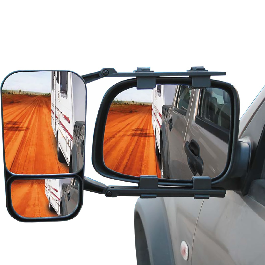 The Drive Towing Mirror, branded by Drive, reflects an RV on a dirt road and provides extended vision. This vehicle-mounted mirror showcases two perspectives: a larger main view and a smaller magnified view below. The image illustrates how the Drive Towing Mirrors enhance visibility for trailers or RVs.