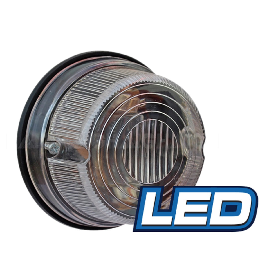 A round LED light from Eagle Eye, with a clear, ribbed lens and a black rubber gasket featuring a slotted design, is shown. The word "LED" appears in blue letters on a white background in the bottom right corner of the image. Known as the Eagle Eye LED Round Trailer Lamp - Reversing, it boasts an impressive 50,000 hours rated life and operates at 12V to ensure long-lasting performance.