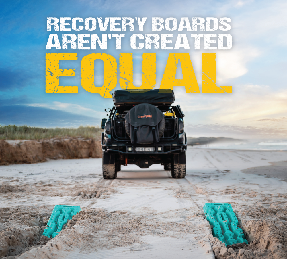 A black off-road vehicle is parked on a sandy terrain with a rooftop tent. Two Aqua Marine Exitrax Recovery Boards from the Ultimate 1150 - Pair + Recovery Board Mounts Bundle are placed in the tire tracks leading away from the vehicle. The text "RECOVERY BOARDS AREN'T CREATED EQUAL" appears above in white and yellow.