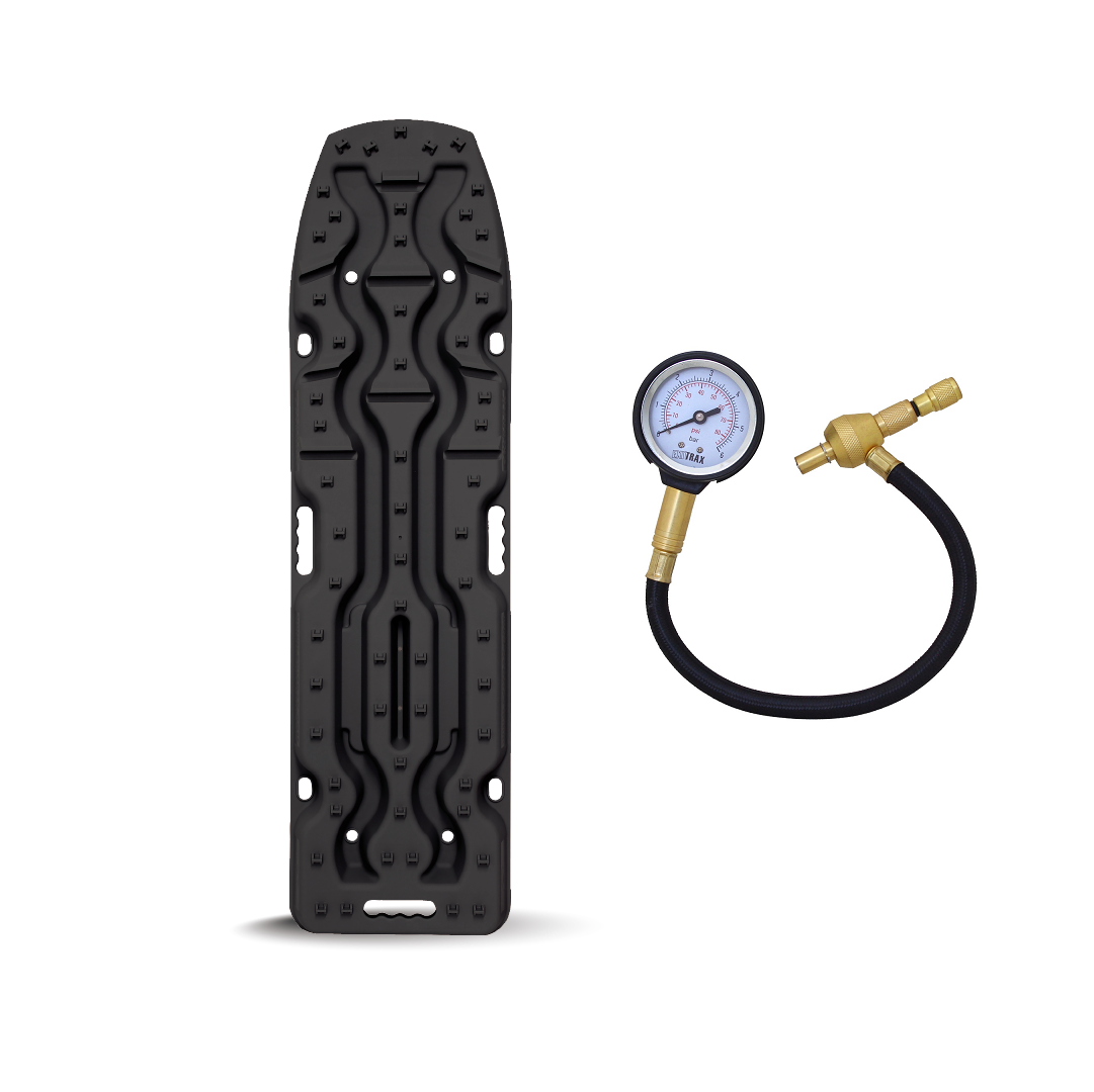 Image featuring the Exitrax Recovery Board Ultimate 1150 - Black, Pair, a vertical, rectangular black plastic panel with various slots and holes. To the right of the board is the free Exitrax Tyre Deflator, which includes a round dial, black hose, and brass fittings.