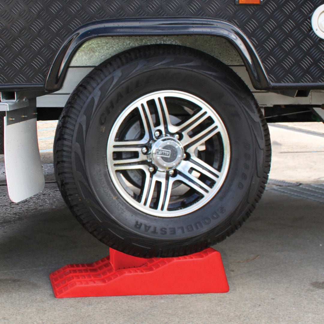 A close-up view of a vehicle's tire resting securely on an Explore Caravan Levelling Ramp—Australian Made—on concrete. The tire and wheel are clean, with the black rubber tire showing clear tread patterns and the metal wheel sporting a shiny finish, thanks to Explore ensuring stability.