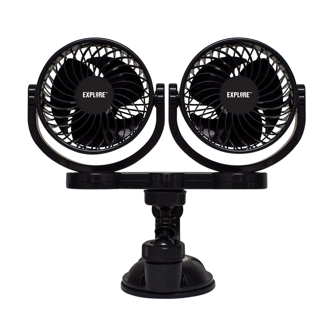 The Explore Twin 12V Fan in black, featuring the "Explore" brand name on each dual-head fan, is mounted on an adjustable base with a heavy-duty suction cup mount at the bottom. The two fan heads are positioned side by side, each equipped with a circular protective grille and variable speed control for personalized comfort.