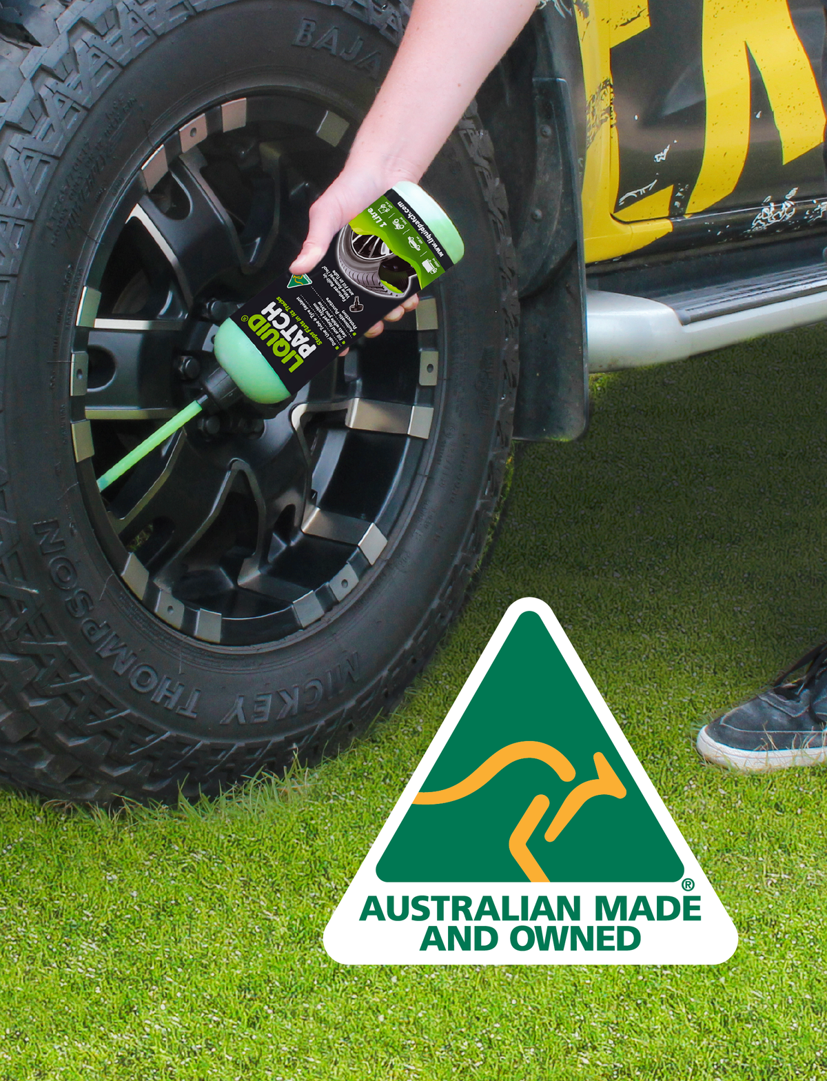 A skilled individual applies Liquid Patch's Tyre Puncture Repair - 500ml to a car tire with a sleek black rim on lush grass. The kangaroo logo states "Australian Made and Owned," underscoring the reliability of this dual-use tube and tyre sealant.