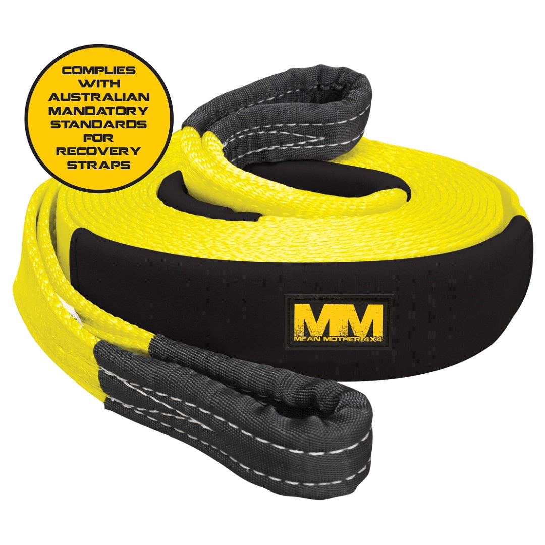 The Mean Mother Snatch Strap 75mm / 9m 11,000kg is a black and yellow strap designed with reinforced ends and visible stitching. Made from durable nylon webbing, it prominently displays the "MM Mean Mother" logo. A yellow circle signifies its compliance with Australian mandatory standards, guaranteeing reliable kinetic energy pulling force during recovery operations.