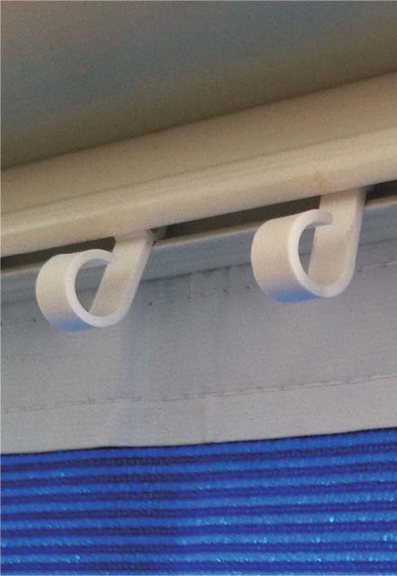 Close-up of two Explore Caravan/RV Awning Rail Hanger Clips from the 10-pack set, featuring a sleek loop design as they attach gracefully to an awning track. These white plastic clips elegantly suspend a blue fabric—likely a curtain or blind—beneath the visible upper section of a metallic rod, making them perfect for caravans or motorhomes that desire both style and functionality.