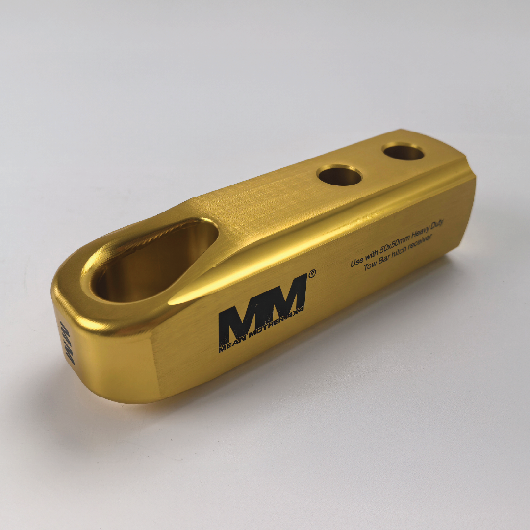 A gold-coloured, rectangular billet aluminium Recovery Hitch with three holes and rounded edges, branded with the "Mean Mother 4x4" logo in black on the side.