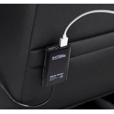 A black Battery Link 4 Port USB Car Charger is attached to the back of a car seat, with a white USB cable plugged into it. The charger, branded as "Battery Link," rests on a gray fabric surface, seamlessly blending power and convenience for your journey.