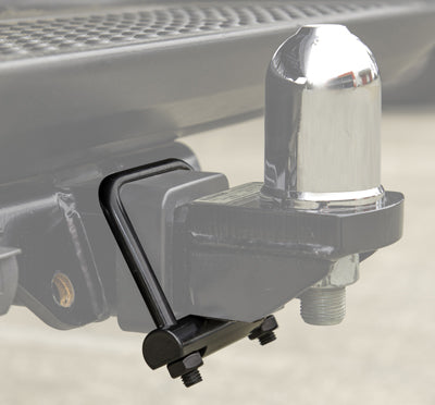 Close-up of a vehicle's tow hitch with a chrome trailer ball attached to the Cargo Mate Tow Hitch Clamp. The black mounting hardware and bolts are visible, securely holding the hitch in place. The background shows part of the vehicle's bumper.